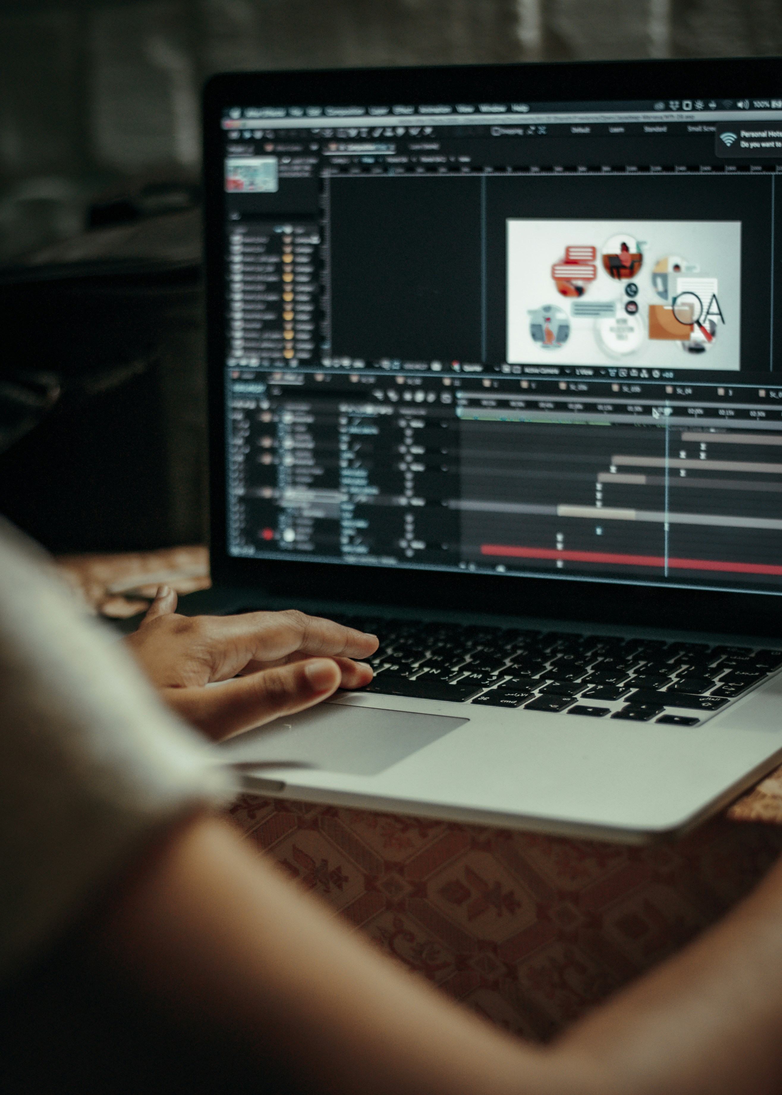 A person working on a laptop, editing an animated explainer video with a timeline visible.